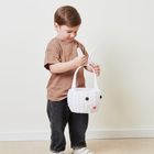 Ein Kind hält einen weißen Korb mit Hasengesicht, großen Augen und rosa Nase, trägt braunes Shirt und dunkle Jeans.