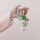 Keine Texte zu sehen. Eine Hand hält einen Schlüsselring mit bunten, lächelnden Filzanhängern und einer Perlenkette.