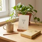 Karte: "Ich bin offen für alles Gute." Umgebung: Pflanze, Tasse, Bleistift auf Tisch, Schachtel mit Text auf der Vorderseite.