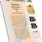 Kalenderblatt für 2027. Überschrift: "Banana Pancake Trail" mit Text über Abenteuerreisen. Illustration von gestapelten Pfannkuchen.