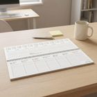Kalender zeigt Januarwoche 4 bis 10. Schreibtisch mit Computer, Notizblock, Stift und Kaffeetasse.