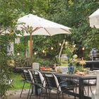 "Juli 2027" und "Landlust" auf einem Kalender. Ein gedeckter Tisch im Garten mit Sonnenschirm, Girlanden und Speisen.