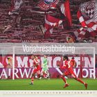 "Vorjahresabbildung" steht im Vordergrund. Dahinter ein belebtes Fußballstadion mit Fahnen und Fans in Rot-Weiß. Spieler im Spiel.
