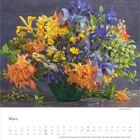 „März“ und Monatskalender darunter. Buntes Blumenarrangement mit gelben, orangenen und blauen Blüten.