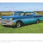 März 2027 Kalender. Ein blauer Oldtimer auf einer Wiese unter blauem Himmel vor einer ländlichen Kulisse.