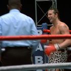 Die Buchstaben "ABA" sind auf einem blauen Boxringpfosten sichtbar. Zwei Boxer im Ring, der eine lächelt, der andere im Angriff.