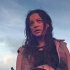 Ich weiß nicht, wer darauf zu sehen ist. Eine Frau mit langen, nassen Haaren blickt besorgt in den Himmel, Wolken im Hintergrund.