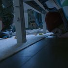 Ein Kind versteckt sich unter einem Bett, während jemand in Militärkleidung im Raum steht. Spielsachen liegen verstreut.