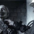 Zwei Personen, eine sieht beängstigend aus, die andere trägt einen Schutzanzug mit Helm, in einer düsteren Umgebung.