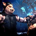 Ein Mann mit Lederrüstung kämpft gegen eine Figur mit Schweinsmaske in einem Waldsetting bei Nacht.