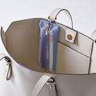 Ein offenes, helles Leder-Handtascheninnere mit einer blauen, durchsichtigen Reißverschlusstasche an der Innenseite.