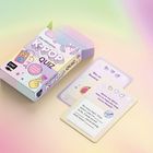 "Das ultimative K-Pop Quiz" steht auf einer schachtel. Zwei Karten mit Herzsymbolen und Fragen sind daneben platziert. Pastellfarbene Optik.