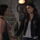 Text: "3K" und weitere unlesbare Zeichen auf der Wand. Zwei Frauen halten Hände und stehen sich ernst gegenüber.