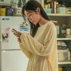 Der Schriftzug "RICHAM" ist auf einer Dose zu sehen. Eine Frau in gelbem Pulli schaut auf ihr Handy, umgeben von Küchengeräten.