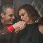 Ein Mann mit grauen Haaren küsst die Hand einer Frau. Beide sind elegant gekleidet. Im Hintergrund sind noch weitere Personen.