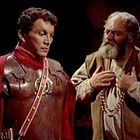 Zwei Männer in historischer Kleidung, links mit Rüstung und Rot, rechts mit Bart, betont seine Brust.