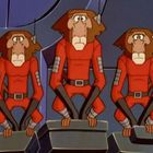 Drei affenartige Figuren in roten Anzügen, hocken auf grauen Blöcken, mit Antennen auf den Köpfen. Animationstil.