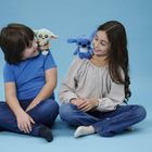 Zwei Kinder sitzen auf einem blauen Hintergrund. Eines hält ein grünes, das andere ein blaues Plüschtier auf der Schulter.