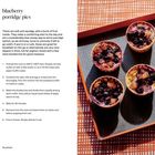 "Blueberry porridge pies" mit Rezepttext. Links Zutatenliste, rechts sechs Muffins auf schwarzem Tablett mit orange-weißem Muster.