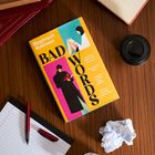 "Ríoghnach Robinson - BAD WORDS" auf einem Buchcover mit moderner Grafik. Drumherum sind Notizpapier, Stifte und zerknülltes Papier.