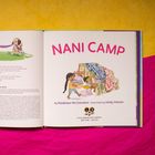 "NANI CAMP" steht in großen, pinken Buchstaben. Eine Illustration zeigt ein Kind, das ein Zelt aus Decken baut.