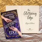 „The Glittering Edge“ von Alyssa Villaire. Ein Buchcover mit Händen und Schmuck, das Buch liegt auf goldenem und silbernem Papier.