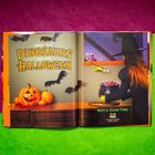 "What the Dinosaurs Did on Halloween." Eine Hexe mit einem Süßigkeitskessel, Kürbisse und fliegende Fledermäuse.