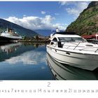 "Hafen von Flåm am Aurlandsfjord." Eine ruhige Wasserlandschaft mit zwei Booten, Bergen und blauem Himmel im Hintergrund. 