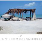 "Fischerboot am Strand." Ein weißes Boot neben einer Hütte aus Holz und Palmen, am Strand mit blauem Himmel und Meer.