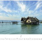 Text: "Überlingen Pfahlbauten". Stimmungsvolles Foto von Pfahlbauten über Wasser unter einem lebhaften Himmel.