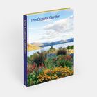 "The Coastal Garden" oben. Hübscher Garten mit bunten Blumen, im Hintergrund Meer und Hügel. Heller Himmel mit Wolken.