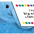 „I have big ears and a long nose.“ Bunte Punkte verzieren den Text. Illustration eines blauen Elefanten.