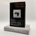 Buch mit dem Titel: "Was zählt ein Mensch?" von Carolin Emcke. Schwarzes Cover mit Bild von schwarzen Pantoffeln.