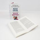 Buchcover: "Wolfgang Schmidbauer, BÖSE VÄTER, KALTE MÜTTER? Reclam". Ein geöffnetes Buch liegt daneben.