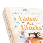 "Fäden des Glücks" von Marit Warncke, Illustrationen von Nähutensilien und einer Nähmaschine auf hellem Hintergrund.