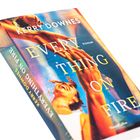 Buchtitel: "Everything on Fire" von Kerry Downes. Darunter ein lachendes Gesicht und ausgestreckte Hände.
