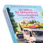 Text: "Sie haben Ihr Hörgerät im Swimmingpool versenkt." Illustration: Ein Auto mit einem Schlauchboot auf dem Dach, Landschaft.