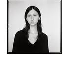 Keine Texte erkennbar. Schwarzweiß-Porträt einer Person mit dunklen Haaren, neutralem Ausdruck und einem dunklen Pullover.