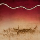 Kein Text. Eine Perlenkette schlängelt sich über rot-beigen Hintergrund, darunter eine Skizze einer mittelalterlichen Stadt.