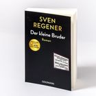 „Sven Regener: Der kleine Bruder. Roman.“ Schwarz-gelbes Cover mit runden und rechteckigen Text-Elementen.
