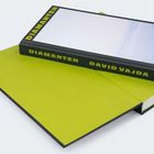 Text: "DIAMANTEN", "DAVID VAJDA". Ein Buch mit schwarzem Einband und gelbem Text, auf grünlichem Untergrund.