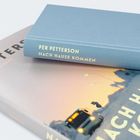 "PER PETTERSON NACH HAUSE KOMMEN" steht auf einem blauen Buchrücken. Das Buch liegt auf einem anderen Buch.