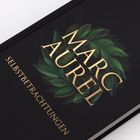 "Marc Aurel" und "Selbstbetrachtungen" stehen in Gold auf schwarzem Hintergrund mit grünen Blättern.