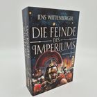 Text: "Jens Wittenberger, Die Feinde des Imperiums, Historischer Roman, Piper." Ein römischer Soldat in Rüstung mit Helm.