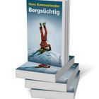 Ein Buchstapel. Titel: "Bergsüchtig" von Hans Kammerlander. Cover: Kletterer kopfüber im Schnee.
