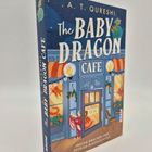 Ein Buchcover mit dem Titel "The Baby Dragon Café". Ein roter Drache schaut aus einem Café heraus.