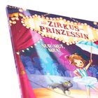 "Die Zirkusprinzessin" und "Nur Mut, Mila!" in großen Buchstaben. Eine fröhliche Illustration eines Mädchens im Zirkus.