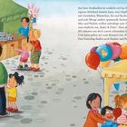 Text: "Auf dem Straßenfest ist wirklich viel los..."  
Illustration: Ein belebtes Straßenfest mit Ständen, Kindern beim Basteln, Luftballons und einer Hüpfburg.