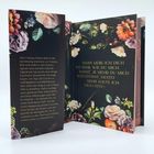 Zwei aufgeschlagene Buchseiten. Links: "Alex Corbeau-Green zählt an der Sorrowsong University...". Rechts: "...eben" Es sind dunkle, florale Verzierungen sichtbar.