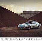 "FEB 21" und "2" unten links. Ein klassisches Auto steht vor Kieshügeln und einem geteilten Himmel.